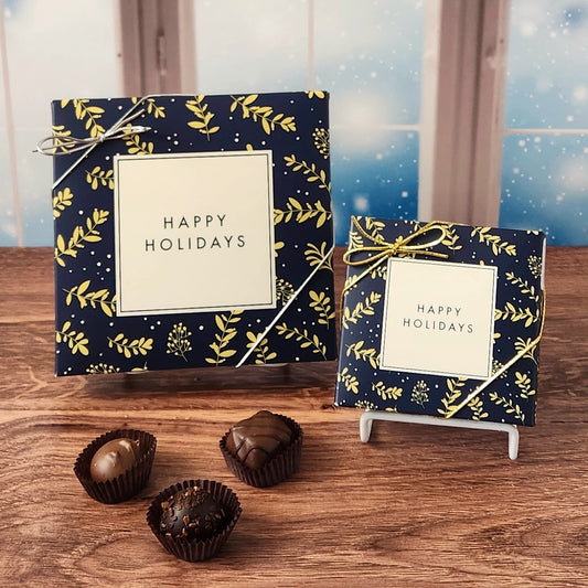 Box of chocolates with  decorative Happy Holidays cover on a wooden surface and snowy background.