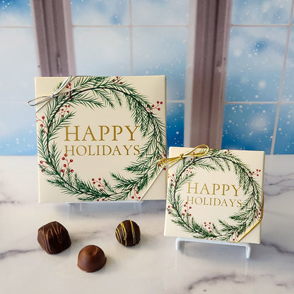 An assortment of our most popular milk and dark chocolate creams, caramels, melt-aways, and truffles all packed inside a box with the words "Happy Holidays" inside a winter wreath printed on the cover.