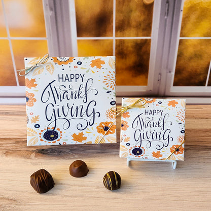 An assortment of our most popular milk and dark chocolate creams, caramels, melt-aways, and truffles all packed inside a box with the words "Happy Thanksgiving" surrounded by fall flowers and leaves printed on the cover.