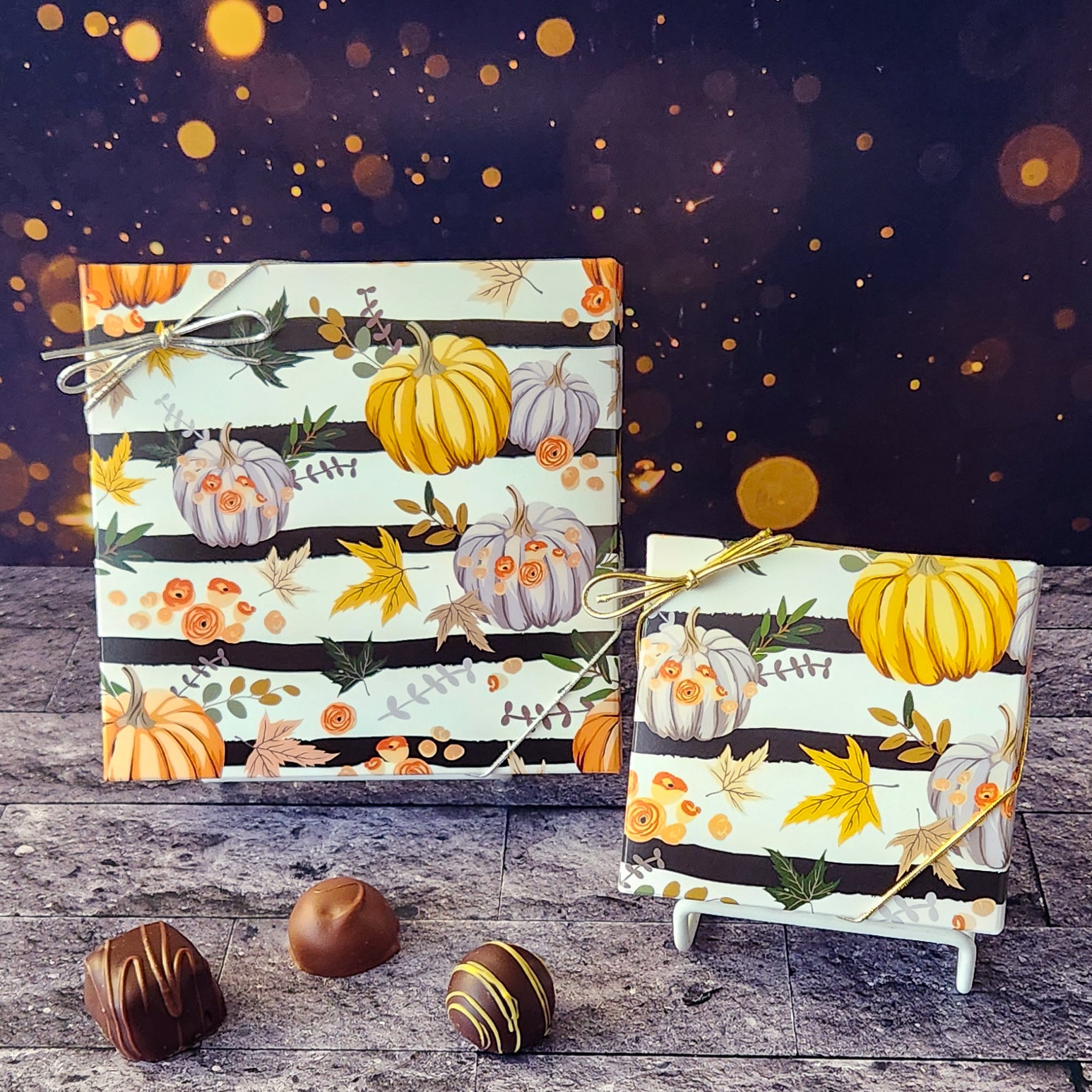 An assortment of our most popular milk and dark chocolate creams, caramels, melt-aways, and truffles all packed inside a box with a festive fall cover featuring leaves, pumpkins against a graphic stripe.