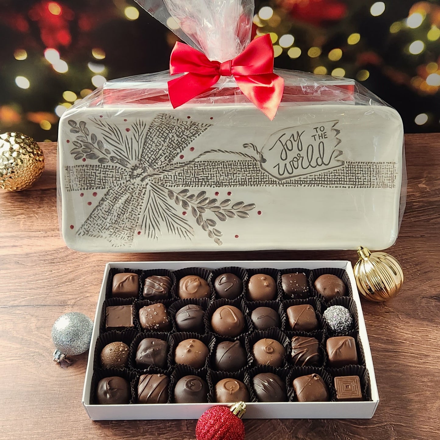 Enjoy 28 pieces of Stage Stop Candy's most popular milk and dark chocolates on a ceramic tray inscribed with "Joy to the World" and festive bow