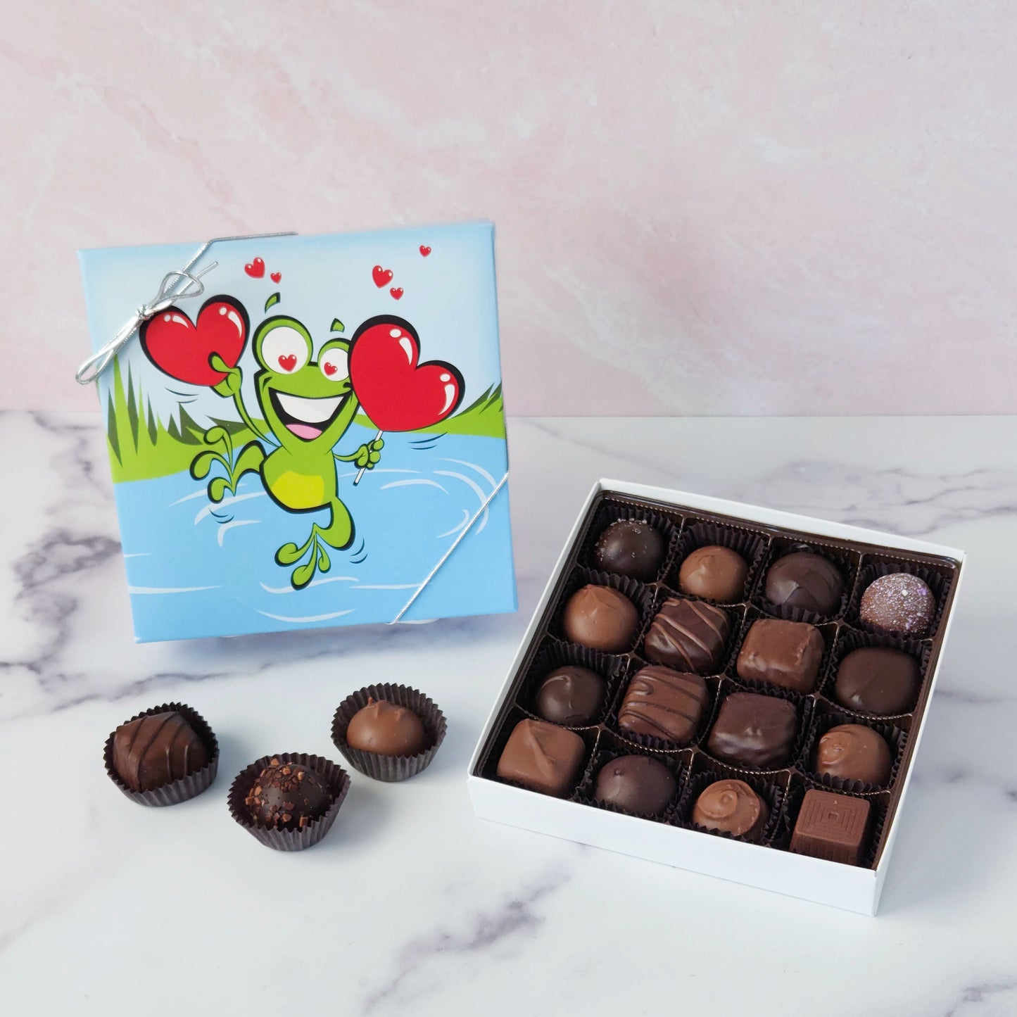 Hop into a world of chocolatey bliss with our Leaping Frog Chocolate Assortment! Bursting with rich milk and dark chocolate favorites, this festive 9-piece or 16-piece box is perfect for anyone who loves a little whimsy with their sweets.
Inside, you'll discover a delicious variety of handmade favorites: silky meltaways, buttery caramels, rich truffles, and smooth, dreamy creams.