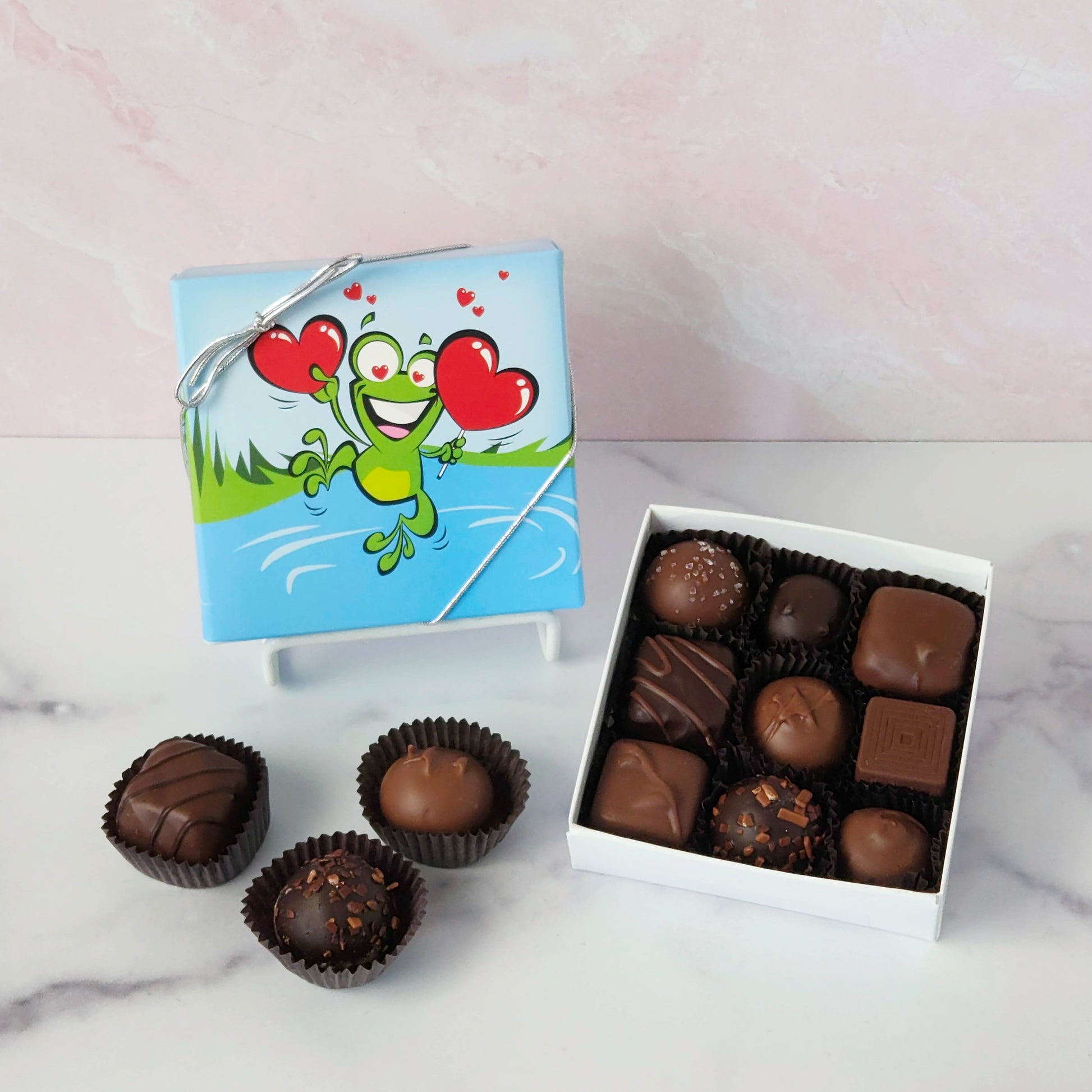 Hop into a world of chocolatey bliss with our Leaping Frog Chocolate Assortment! Bursting with rich milk and dark chocolate favorites, this festive 9-piece or 16-piece box is perfect for anyone who loves a little whimsy with their sweets.
Inside, you'll discover a delicious variety of handmade favorites: silky meltaways, buttery caramels, rich truffles, and smooth, dreamy creams.