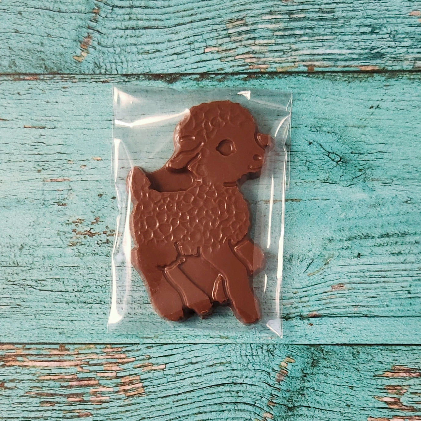 Chocolate lamb in a clear plastic bag on a textured blue wooden surface