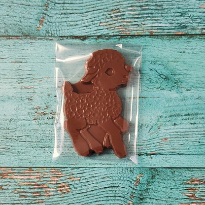 Chocolate lamb in a clear plastic bag on a textured blue wooden surface