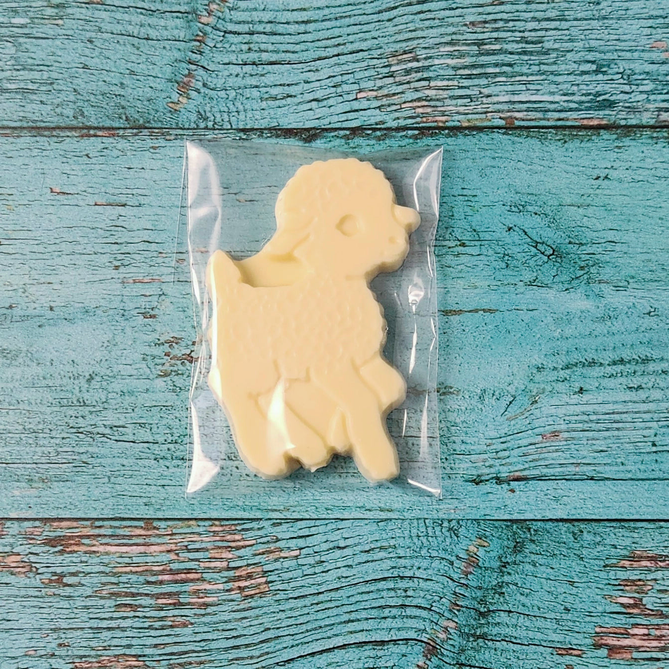 Lamb-shaped white chocolate in clear packaging on a blue wooden surface