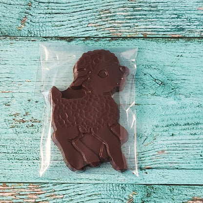 Chocolate Lamb-shaped mold in clear plastic on a textured blue wooden surface