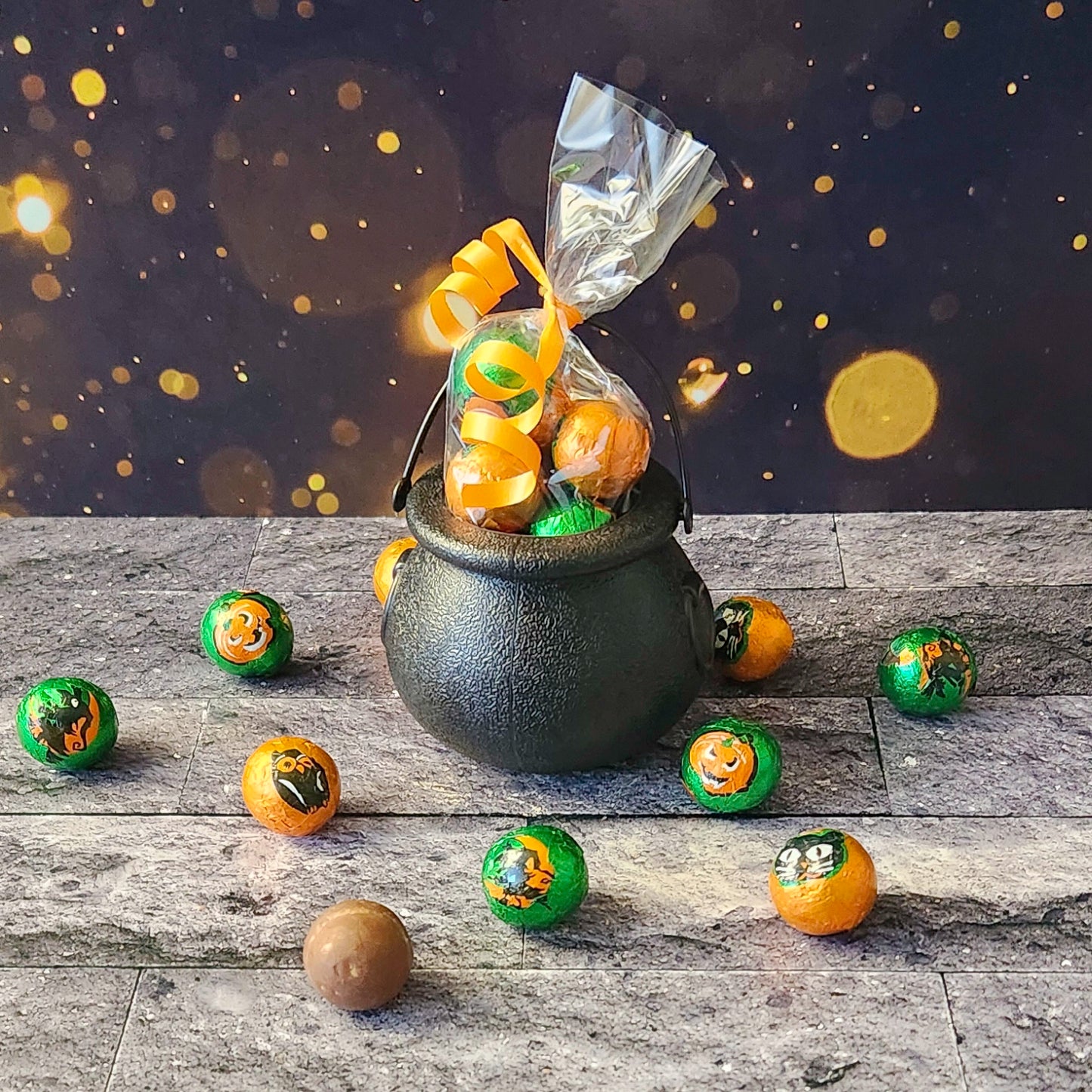 Get ready to brew up some Halloween magic with our Halloween Kettle Filled with Foiled Milk Chocolate Balls! This fun, festive plastic kettle comes pre-filled with 10 delicious milk chocolate balls, each wrapped in spooky foil designs to add a touch of frightful fun to your celebrations.