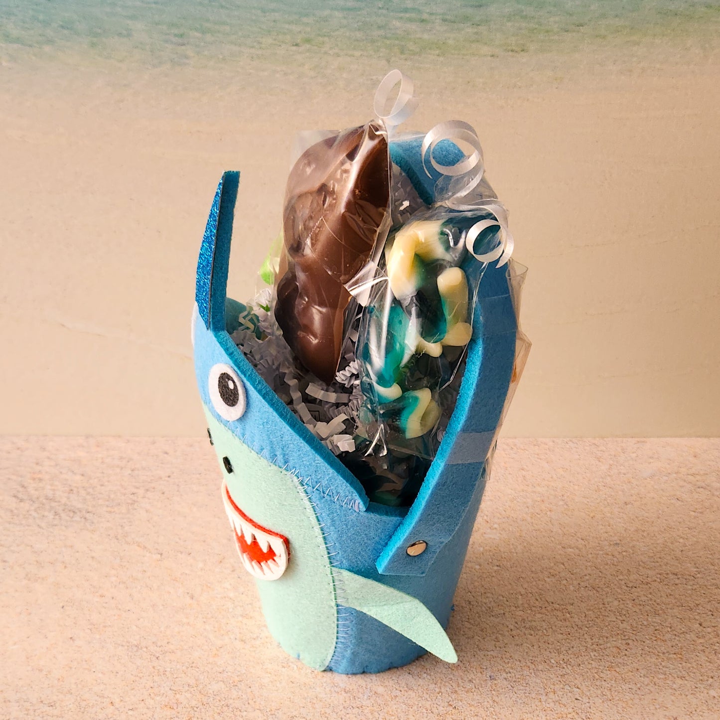A milk chocolate shark lollipop and baby gummy sharks fill up our shark themed basket.