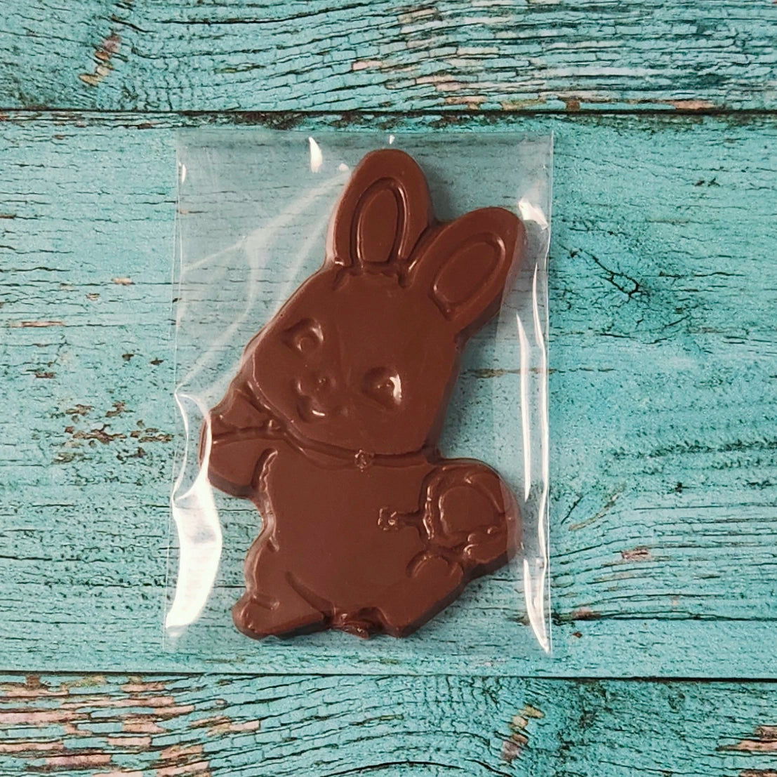 Chocolate bunny in a clear bag on a rustic wooden surface