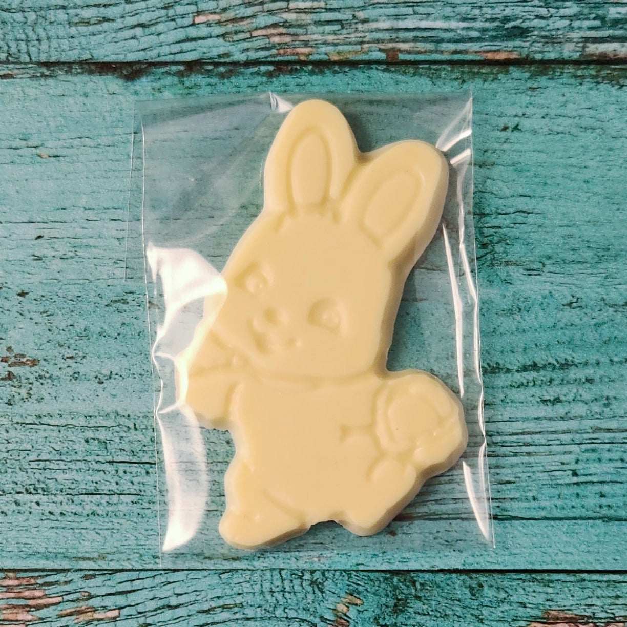 White chocolate bunny shaped like a rabbit on a rustic wooden surface