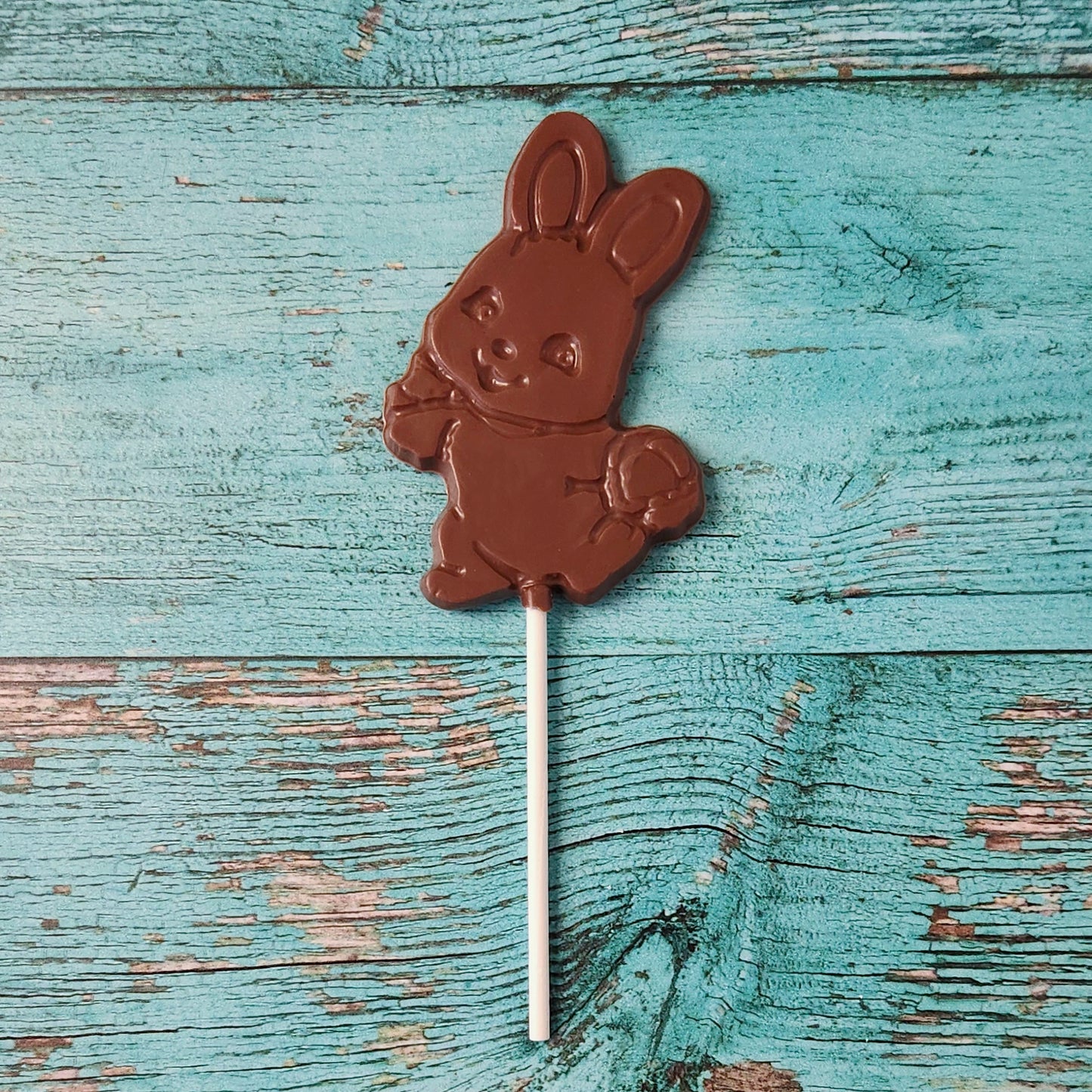 Chocolate bunny on a stick against a rustic wooden background