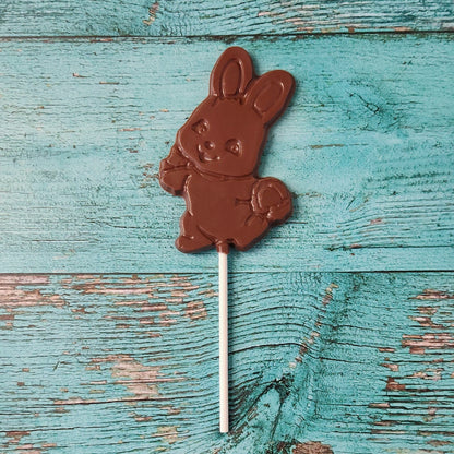 Chocolate bunny on a stick against a rustic wooden background