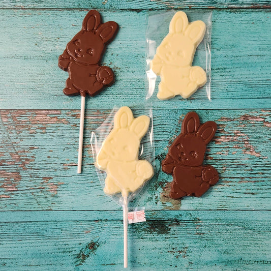Chocolate and white bunny lollipops on a rustic wooden surface