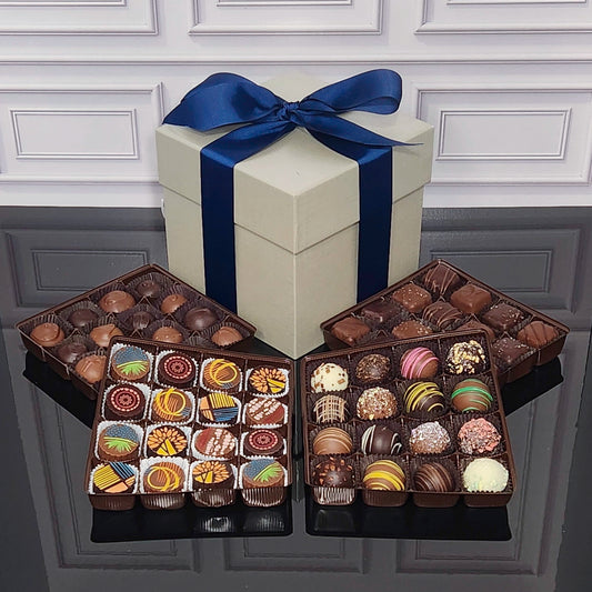 Assorted Chocolates in front of a gift box wrapped with a blue bow