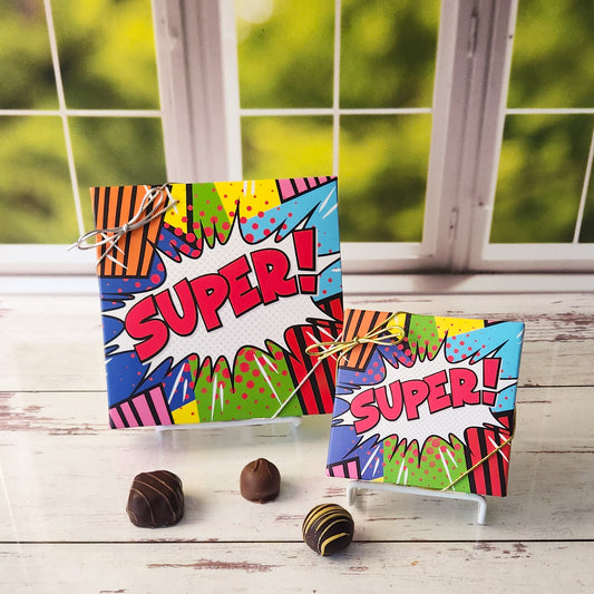 An assortment of our most popular milk and dark chocolate creams, caramels, melt-aways, and truffles all packed inside a festive box. On the cover the word Super is written against as colorful comic book style backdrop is printed.