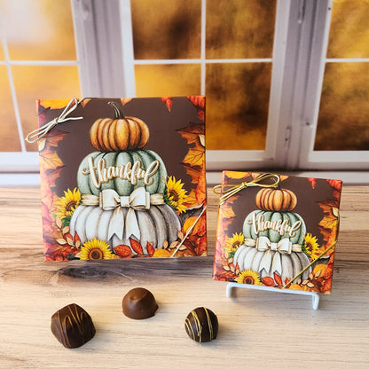 An assortment of our most popular milk and dark chocolate creams, caramels, melt-aways, and truffles all packed inside a box with the words "Thankful" written across a stack of fall pumpkins printed on the cover.