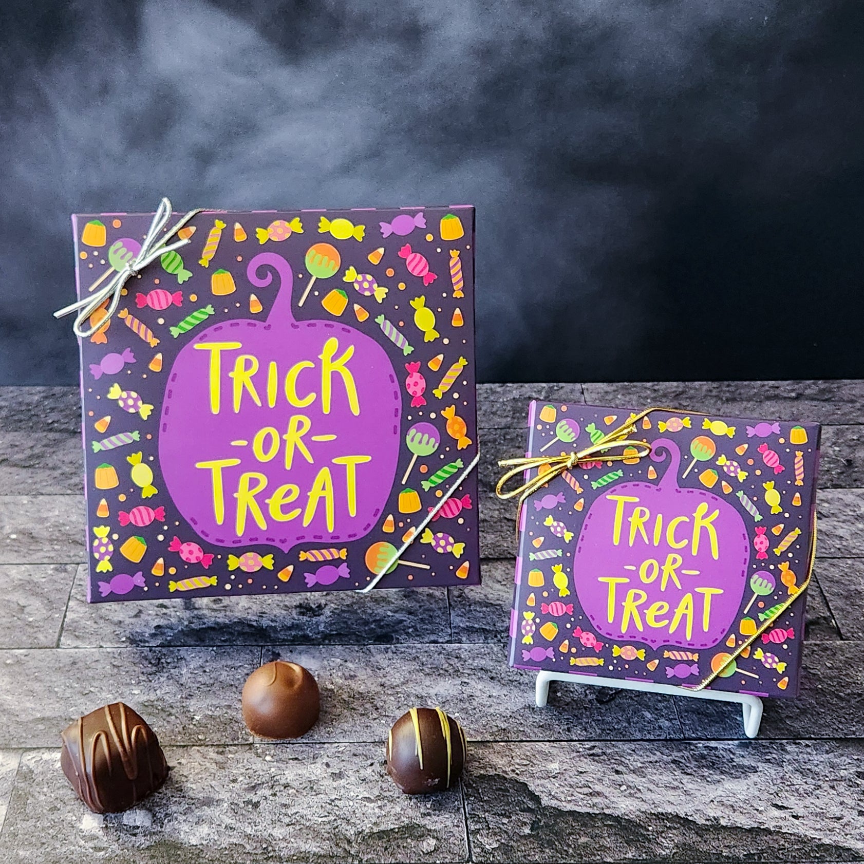 An assortment of our most popular milk and dark chocolate creams, caramels, melt-aways, and truffles all packed inside a box with the words Trick or Treat surrounded by candy printed on the cover.