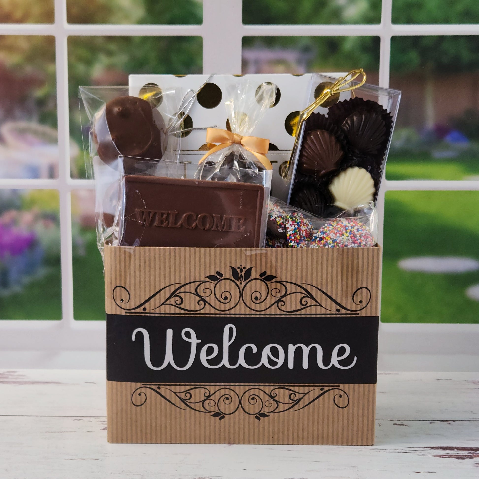 Our Welcome Gift Basket is filled with thoughtful treats  including: 
Milk, Dark & White Chocolate Sea Shells,  Milk Chocolate Nonpareils,  Dark Chocolate Covered Cranberries,  Two Chocolate Covered Oreos, a "Welcome" Milk Chocolate Bar and a 16-Piece Chocolate Assortment – filled with creams, caramels, meltaways, and truffles.  All overwrapped with a bow and ready for gifting.