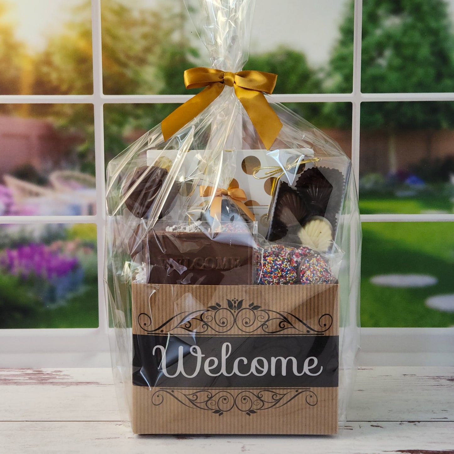Our Welcome Gift Basket is filled with thoughtful treats  including: 
Milk, Dark & White Chocolate Sea Shells,  Milk Chocolate Nonpareils,  Dark Chocolate Covered Cranberries,  Two Chocolate Covered Oreos, a "Welcome" Milk Chocolate Bar and a 16-Piece Chocolate Assortment – filled with creams, caramels, meltaways, and truffles.  All overwrapped with a bow and ready for gifting.