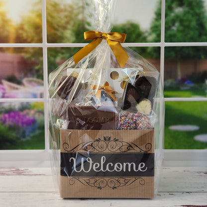 Our Welcome Gift Basket is filled with thoughtful treats  including: 
Milk, Dark & White Chocolate Sea Shells,  Milk Chocolate Nonpareils,  Dark Chocolate Covered Cranberries,  Two Chocolate Covered Oreos, a "Welcome" Milk Chocolate Bar and a 16-Piece Chocolate Assortment – filled with creams, caramels, meltaways, and truffles.  All overwrapped with a bow and ready for gifting.