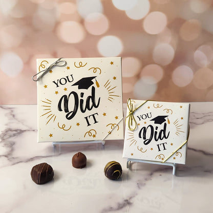 An assortment of our most popular milk and dark chocolate creams, caramels, melt-aways, and truffles all packed inside a festive box. On the cover of the box the saying You Did It! with a graduation cap is printed.