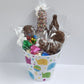 Baby Gift Basket includes Milk Chocolate Nonpareils, Milk Chocolate covered Oreos, Shortbread Cookies, and a M&M-covered pretzel,  blue, gold, pink, and green foiled milk chocolate hearts, milk chocolate teddy bears and a baby bottle lollipop!