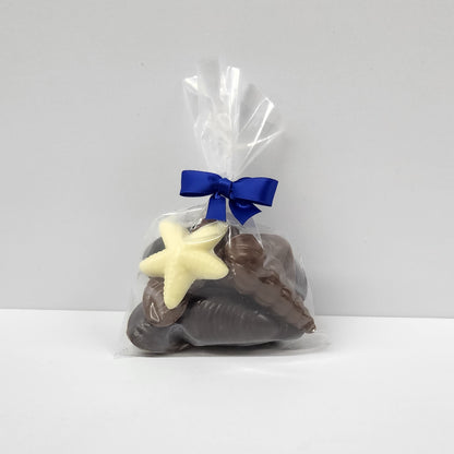 A bag of Milk, Dark and White Chocolate shells and sea creatures wrapped in a bag and tied with a blue ribbon