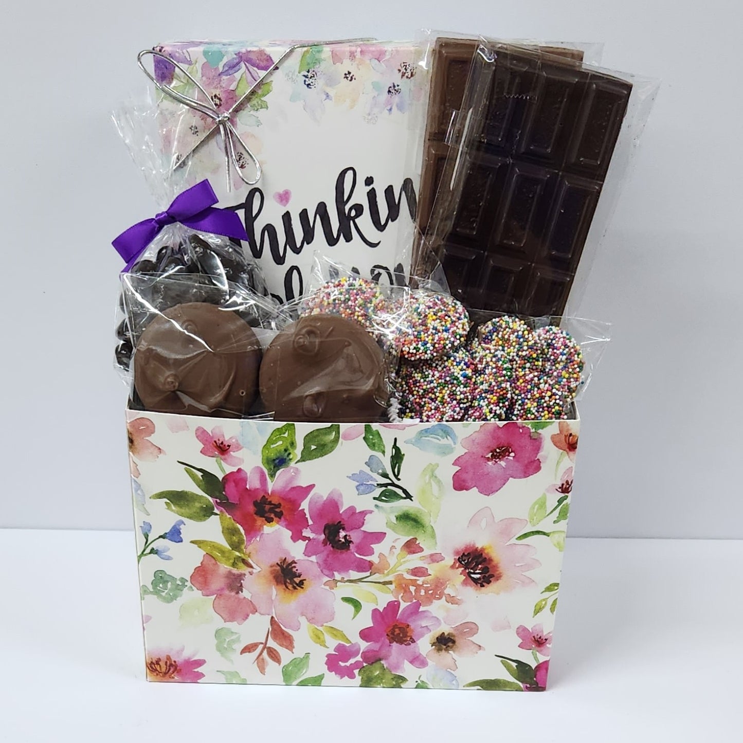 Watercolor Flower Thinking of You Chocolate Gift Basket inclues milk and dark chocolate candy bars, dark chocolate covered cranberries, milk chocolate covered Oreos and milk chocolate nonpareils. Plus, our 16-piece assortment of creams, caramels, meltaways and truffles