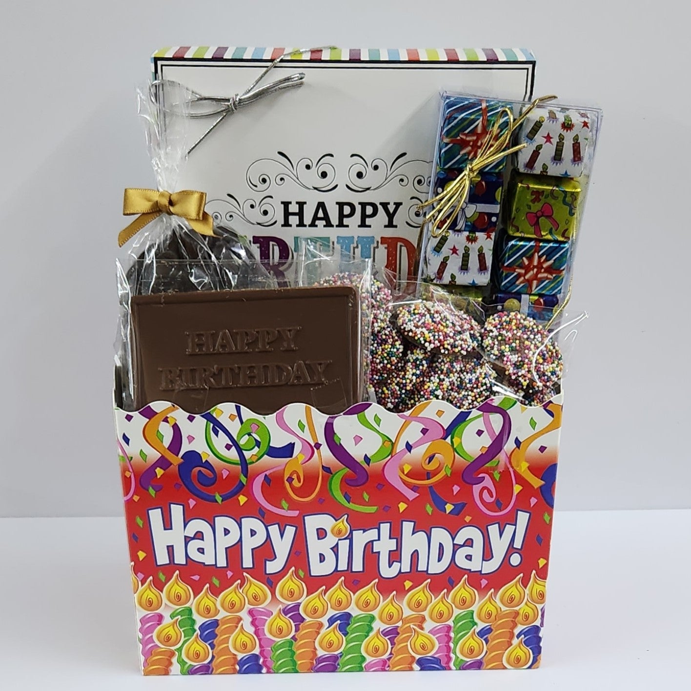 Fun themed Happy Birthday Gift Basket includes foiled milk chocolate presents, milk chocolate nonpareils, dark chocolate-covered cranberries, milk chocolate birthday card and a 16-piece cream, caramels, meltaways, and truffle assortment