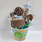 It's a Boy Gift Basket includes Milk Chocolate Nonpareils, Milk Chocolate covered Oreos, Shortbread Cookies, and M&M-covered pretzel, blue and green foiled milk chocolate hearts and a special milk chocolate card and lollipop that say "It's a Boy!".