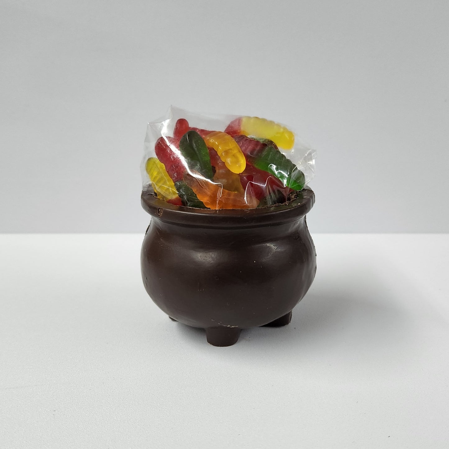 A 3D dark chocolate kettle filled with Salt Water Taffy and Gummy Worms.