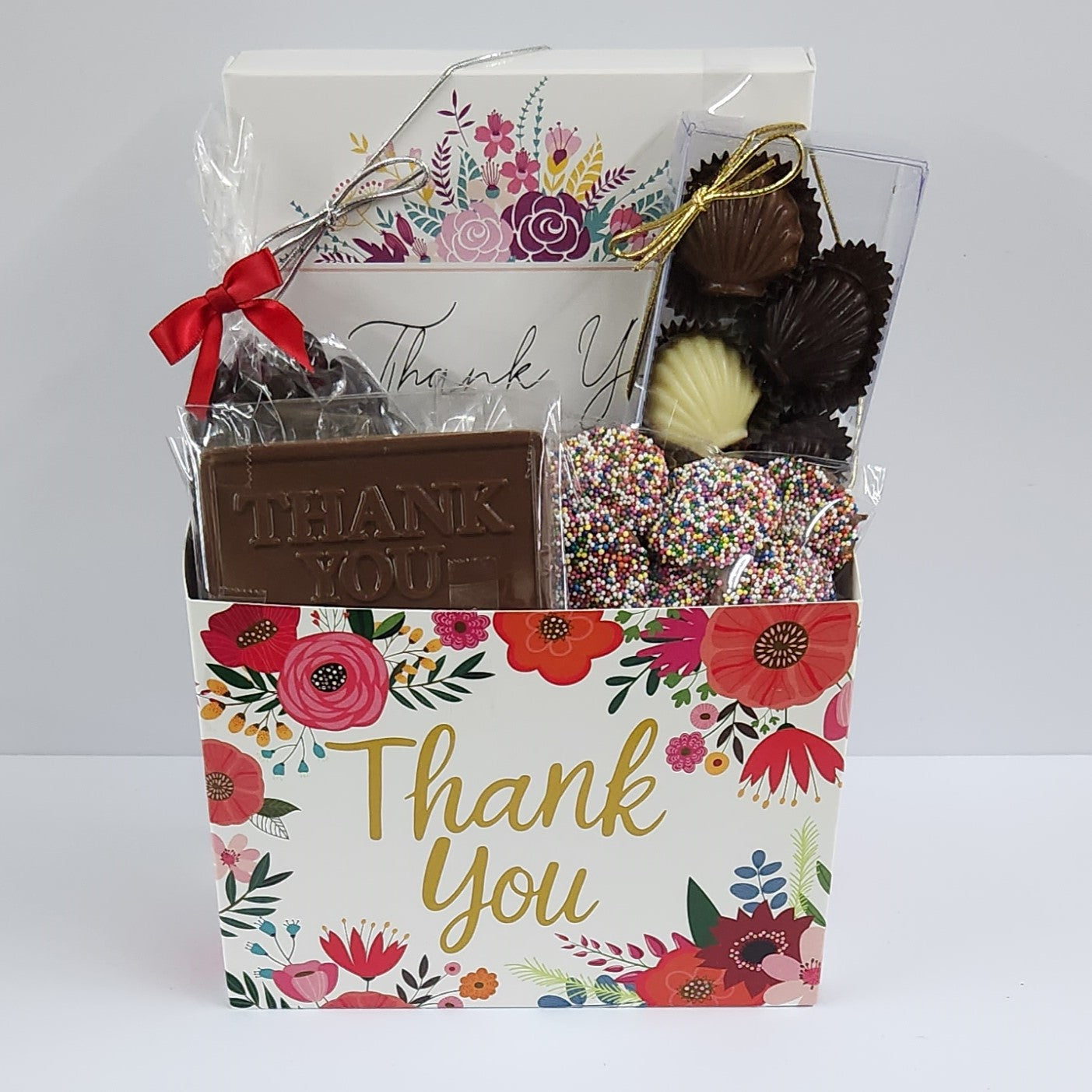 Thank You Floral Gift Basket from Stage Stop Candy features Milk, Dark and White Chocolate Shell Assortment, a Milk Chocolate card that says "Thank You," and Dark Chocolate covered Cranberries, and a 16 piece Thank You Box assortment featuring Creams, Caramels, Meltaways, and Truffles