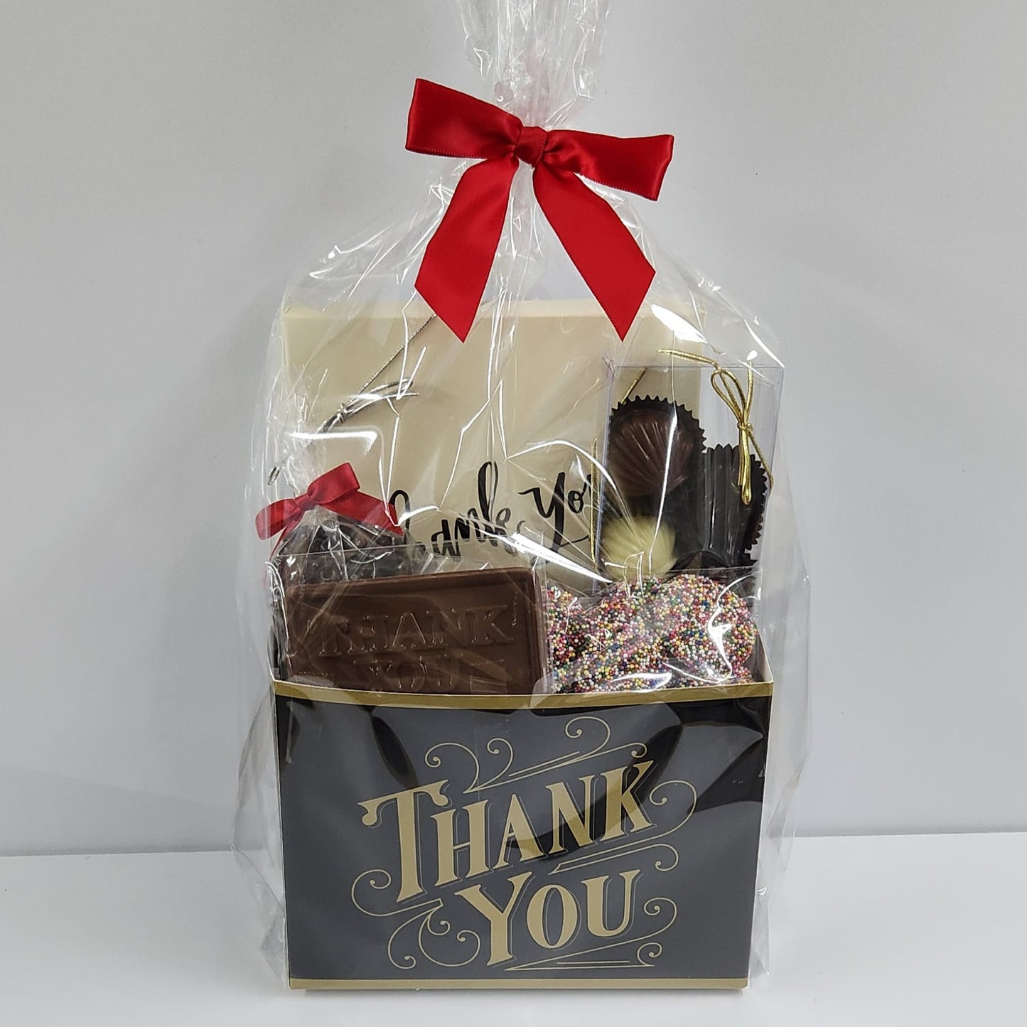 Black and Gold Thank You Gift Basket wrapped with plastic and a red bow